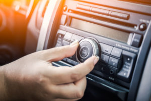 Image of a woman turning the dial on a car radio.